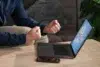 A person in a blue shirt clenches their fists in excitement while sitting in front of a laptop displaying a colorful bingo game screen.