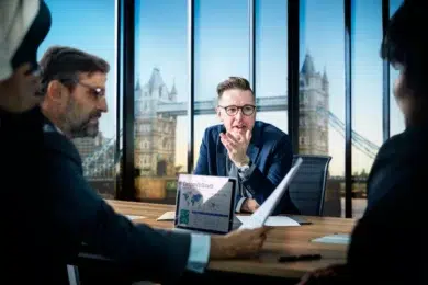 A professional group of accountants in a high-rise London office reviews financial growth charts on a laptop, illustrating the role of a CPA in an IPO process.