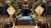Elegant wedding venue with crystal chandeliers, floral decorations lining a glass runway, and banquet tables with white chairs and linens.