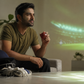 Cricket fan watching a live match online on a mobile device with a stadium scene in the background