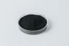 Black powder in a clear round petri dish on a light gray background.