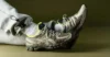 Person wearing gray sweatpants and neon-accented beige athletic shoes, resting feet against a plain olive background.