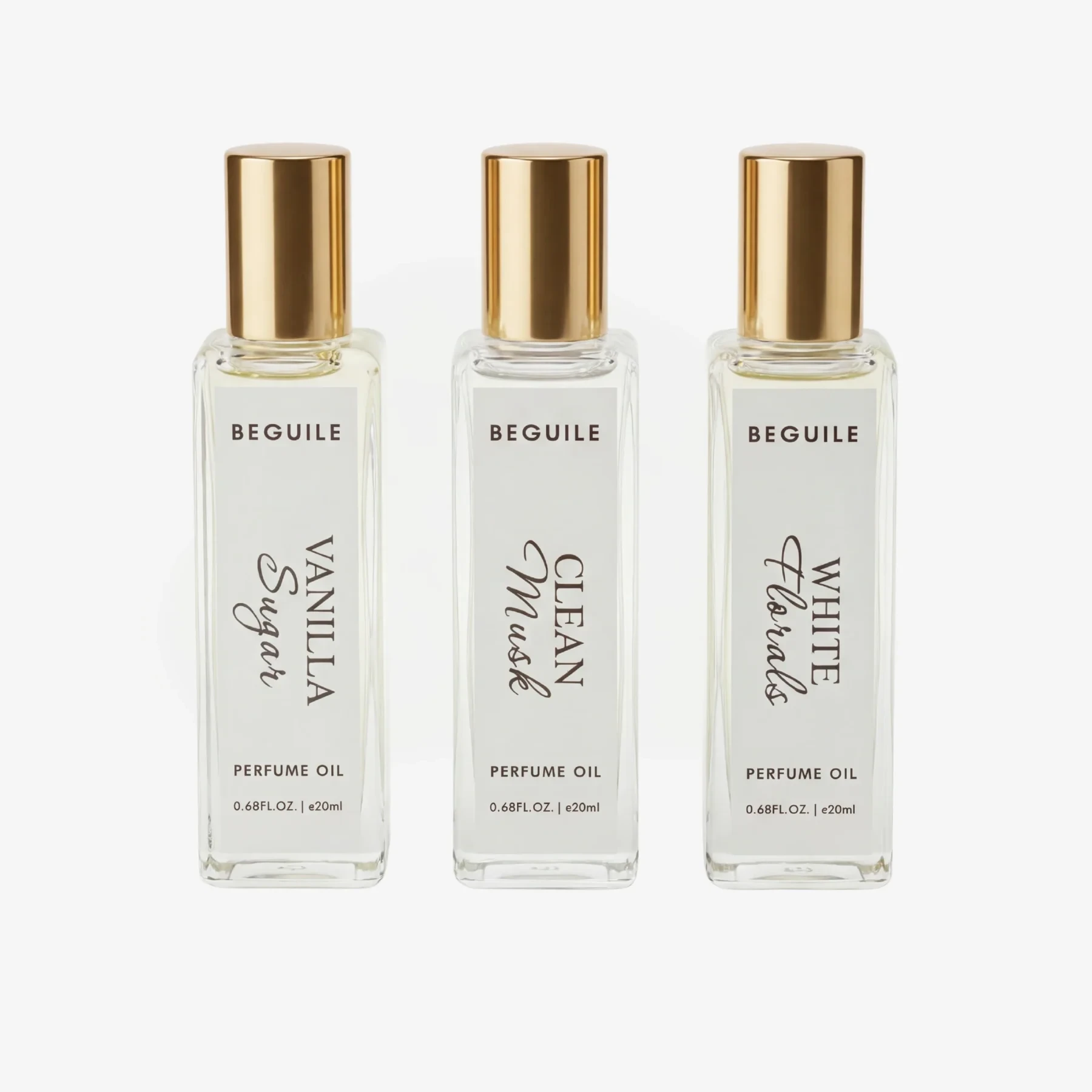 Three Beguile perfume oil bottles with gold caps labeled Vanilla Sugar, Clean Musk, and White Florals.