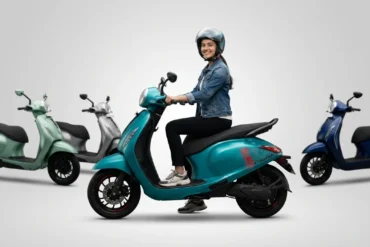 Woman in a helmet riding a teal Chetak electric scooter, with other scooters in various colors behind her.