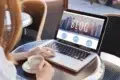 Woman working on a laptop with the word "BLOG" displayed on screen, a cup of coffee beside her.