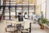 Three people converse in a modern office with bookshelves and collaborative workspaces.