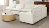 Modern white sectional sofa with plush cushions in a bright living room, featuring a round wooden coffee table on a beige rug.