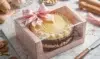 Chocolate cake with cream frosting and pink sugar flowers in a pink gift box decorated with a pink ribbon bow.