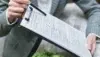 A person holding a clipboard with documents, showcasing a professional setting and paperwork for review or signing.
