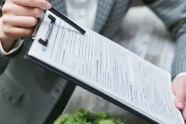 A person holding a clipboard with documents, showcasing a professional setting and paperwork for review or signing.