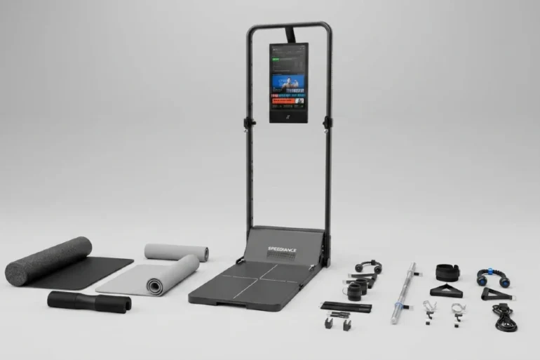 Foldable treadmill with built-in screen, accompanied by various fitness accessories and mats arranged on a plain surface.