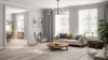A bright, modern living room with a cream sofa, blue and beige pillows, and a wooden coffee table. Large windows, grey curtains, and green plants add a fresh touch.