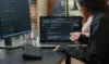 Two people analyze code on a laptop screen, discussing a programming project. A desktop monitor and keyboard are visible, creating a collaborative tech scene.
