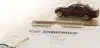A car insurance form lies on a table with a pen and a car key nearby. A small toy car rests on the form, symbolizing automobile coverage.