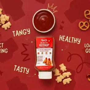 Bottle of healthy ketchup with a bowl of sauce, teddy bear snacks, and pretzels on a red background. Words: "Tangy," "Tasty," "Healthy," "Perfect for Pairing."