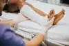 A person in medical gloves adjusts a white cast on a patient's leg and foot.
