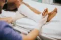 A person in medical gloves adjusts a white cast on a patient's leg and foot.