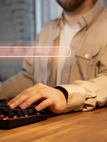Man typing on a backlit keyboard with a search bar graphic overlaid.