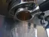 Fresh espresso pours from a coffee machine's portafilter into a clear glass below.