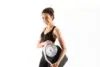 Woman in athletic wear smiling while holding a scale.