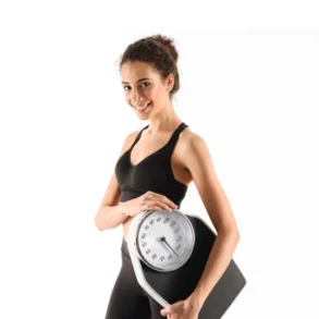 Woman in athletic wear smiling while holding a scale.
