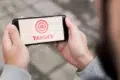 Person holding a smartphone displaying a red target symbol and the word "TARGET" in red text.