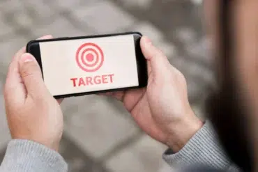 Person holding a smartphone displaying a red target symbol and the word "TARGET" in red text.