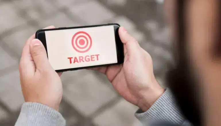 Person holding a smartphone displaying a red target symbol and the word "TARGET" in red text.