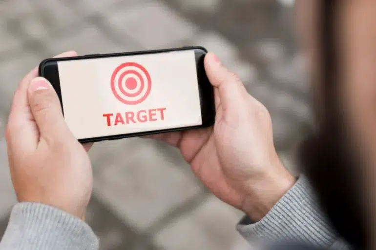 Person holding a smartphone displaying a red target symbol and the word "TARGET" in red text.