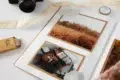 Open scrapbook with travel-themed photos, camera, and colored pencils.