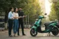 Three people stand on a sunlit street, smiling and discussing near a turquoise electric scooter. Icons highlight insurance benefits like coverage and assistance.