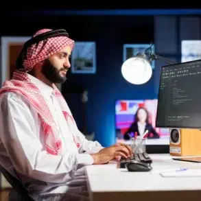 A man in traditional Middle Eastern attire sits at a desk, focused on a computer screen displaying code. The room is dimly lit with a modern, tech-savvy ambiance.