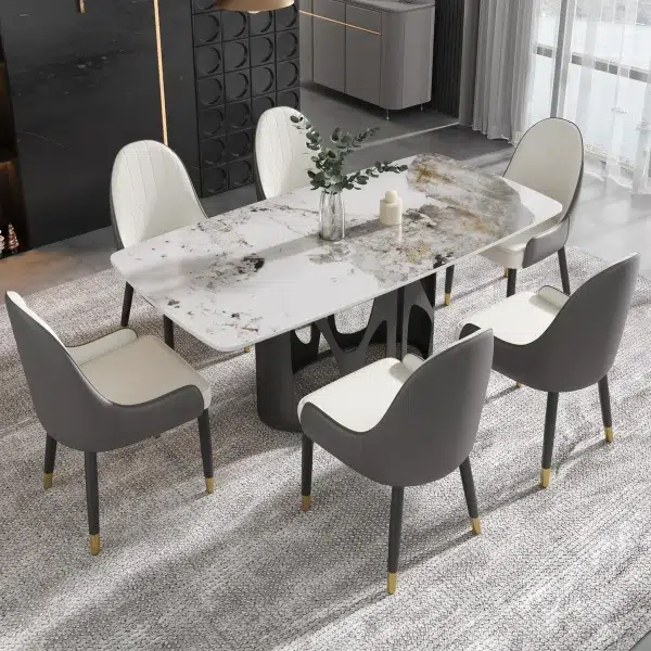 Modern dining room with a marble-top table, six gray and white cushioned chairs, a vase with greenery, and a candle centerpiece.