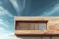 Modern wooden house facade with horizontal slats over a large window under a partly cloudy sky.
