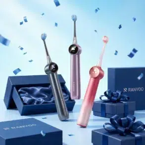 Three colorful electric toothbrushes stand upright amid floating blue confetti. Nearby are elegant blue gift boxes with silky interiors and dark blue ribbons, creating a festive and modern vibe.