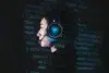 Profile view of a person wearing illuminated headphones with a microphone against a dark background filled with glowing blue code.