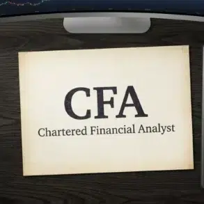 A desk with a paper reading "CFA Chartered Financial Analyst," a calculator, a pen, and a computer monitor displaying a stock chart.
