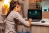 Frustrated woman holds her head while looking at a laptop screen displaying "ACCESS DENIED."