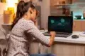 Frustrated woman holds her head while looking at a laptop screen displaying "ACCESS DENIED."