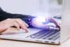 Close-up of hands typing on a laptop with a glowing cloud icon and network graphics overlayed.