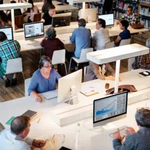 Diverse group of people working on computers in a library or study hall.
