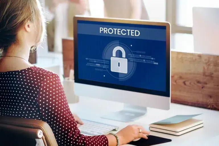 Woman at computer with screen displaying a large padlock icon and the word "PROTECTED".