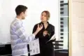 Man in a striped shirt discusses a document with a woman in a black shirt holding a pen.