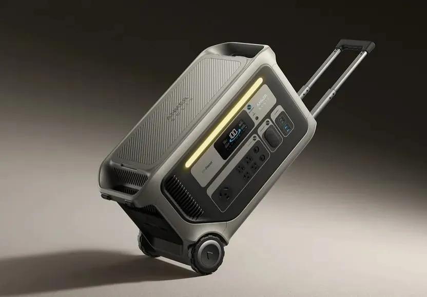 Portable gray power station with wheels, a telescoping handle, digital display, outlets, and a glowing light panel.
