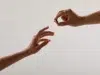 Two hands reach out, one offering a small ring while the other receives it.