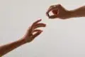 Two hands reach out, one offering a small ring while the other receives it.