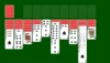 A game of Solitaire is set up with seven columns of face-down and face-up playing cards on a green background.