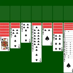 A game of Solitaire is set up with seven columns of face-down and face-up playing cards on a green background.