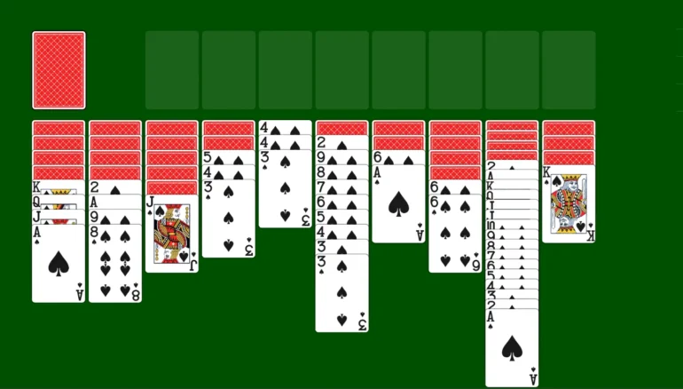 A game of Solitaire is set up with seven columns of face-down and face-up playing cards on a green background.
