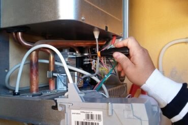 Technician's hand connecting wires inside a boiler.